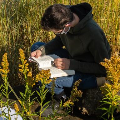 一名联合国环境研究学生坐在田野里记录数据